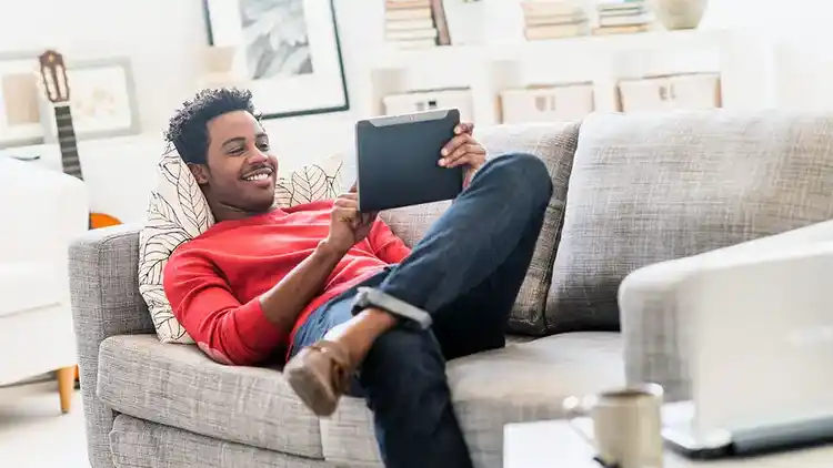 Man on couch looking at iPad